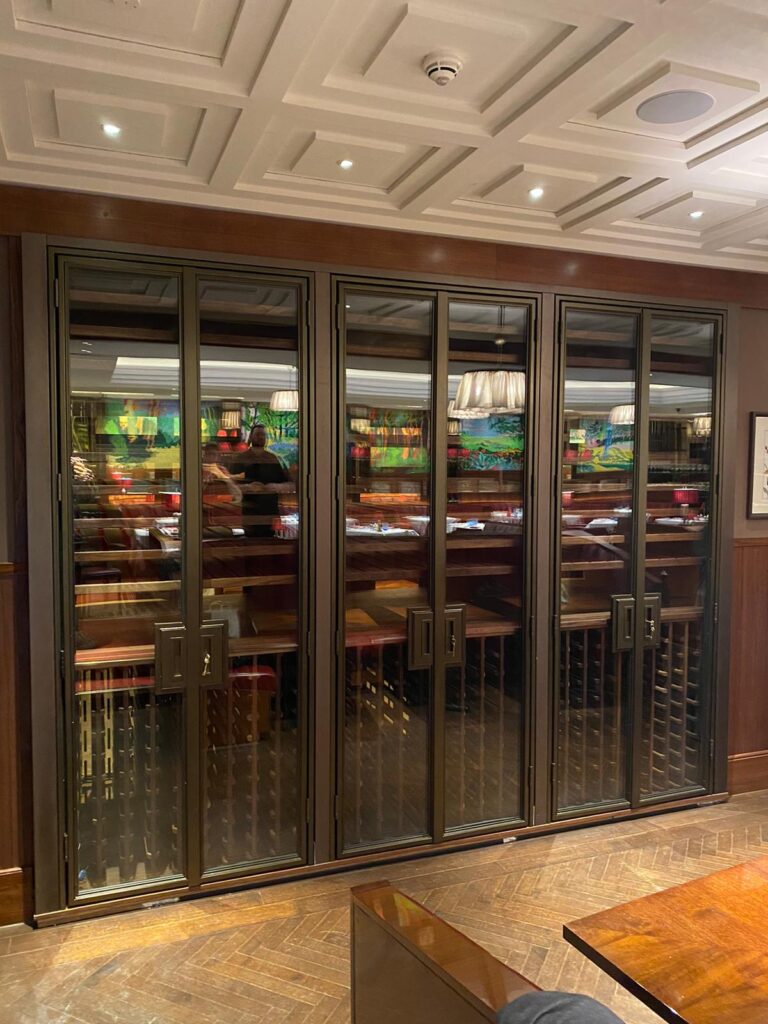 The Beaumont hotel wine walls. Three metal wine walls sit side by side with wooden racking behind double opening doors.