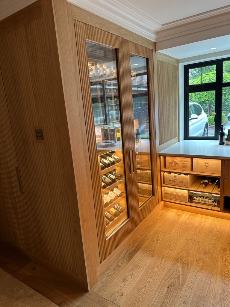 a wine wall on the left wall. The wine wall has been made from a light oak timber and has wine racks behind glass doors.