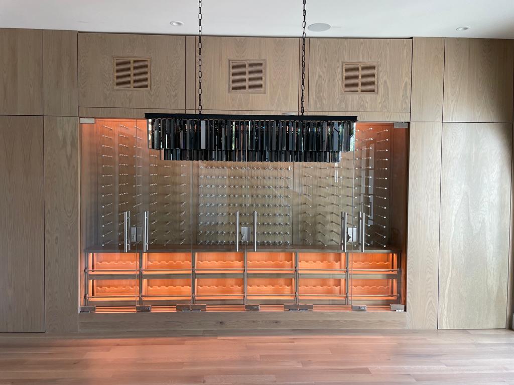 Modern glass wine wall, located in Dallas, with metal wine pegs